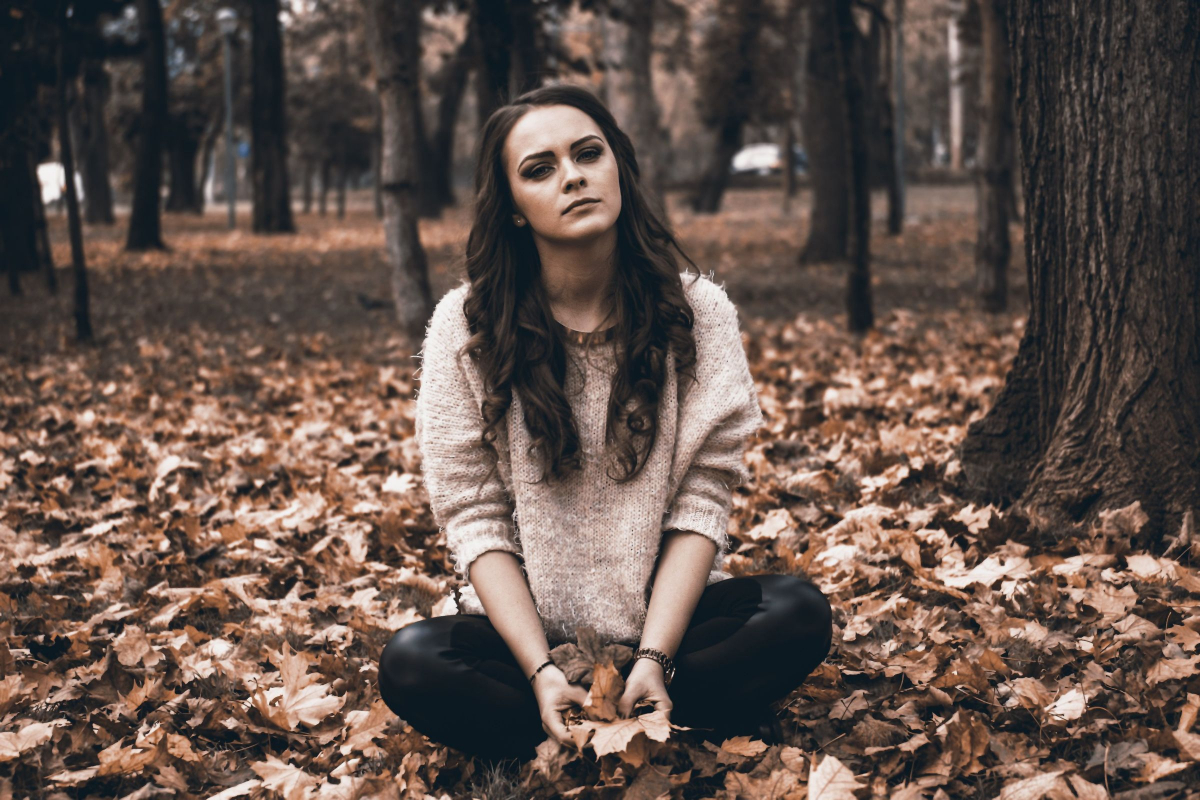 depressed woman sitting in the leaves